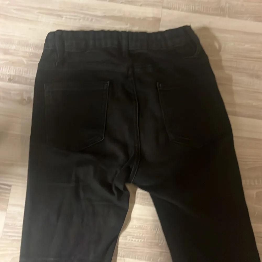 Snygga svarta bootcut byxor med klassisk design. De har en knapp och dragkedja framtill samt fickor bak. Perfekta för en stilren look.. Farkut & Housut.
