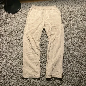 Beige linnebyxor med resårmidja - Säljer ett par bekväma beige linnebyxor med resårmidja och snörning. Perfekta för en avslappnad stil. Byxorna har en loose passform och är tillverkade i ett lätt och luftigt material.