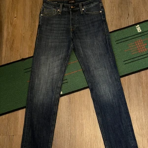 Mörkblå jeans från Jack & Jones - Snygga mörkblå jeans från Jack & Jones i modellen Slim Straight Tim. De har en klassisk femficksdesign och är tillverkade i ett slitstarkt denimtyg. Perfekta för en stilren look. Storlek 29/30 helt nya.