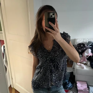 Mönstrad blus i blått och vitt - Säljer en snygg blus med paisleymönster i blått och vitt från pepe jeans. Blusen har korta ärmar och en knytning framtill. Perfekt för en avslappnad stil med jeans.