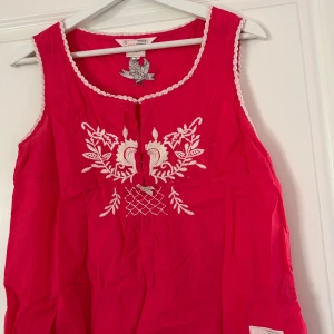Rosa ärmlös blus med broderi från Odd Molly - Säljer en snygg rosa ärmlös blus från Odd Molly med vackert vitt broderi framtill. Blusen har en rund halsringning med spetsdetaljer och ett unikt mönster. Perfekt för en somrig look! Blusen är i fint skick, vid frågor och funderingar hör av er, jag svarar så fort jag kan!🩷
