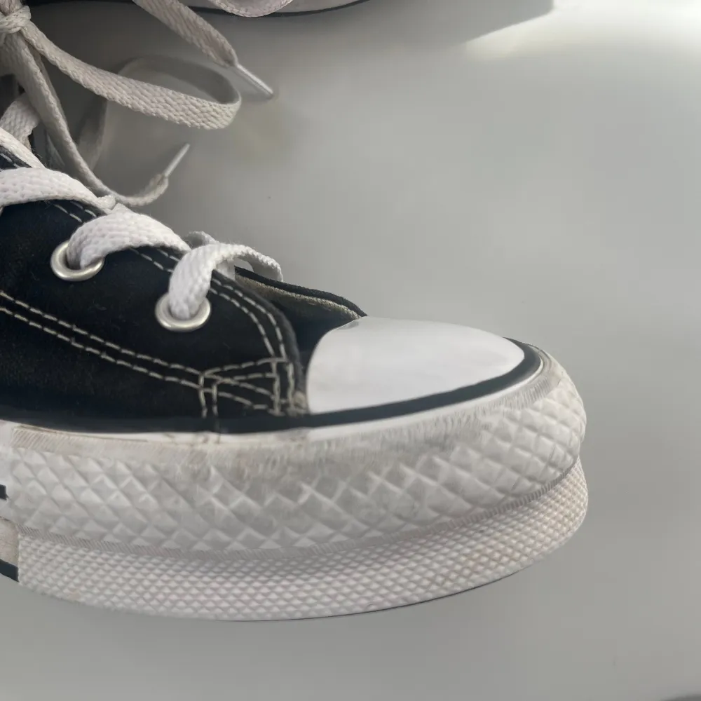 Säljer ett par klassiska svarta Converse All Star sneakers i hög modell. De har vita snören med Converse-märket på sidan.💕Har tvättat skorna+skosnörerna. De är lite slitage framtil på ena skon (bild 4) även lita slitage i hälarna. Annars är de i väldigt bra skick💕 . Kengät.