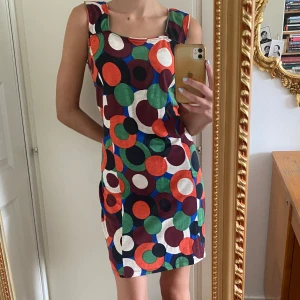 Färgglad klänning med 70-talsmönster - Färgglad, bekväm och lössittande klänning från Indiska men köpt second hand. Bomullstyg med breda axelband. Ungefär midi-längd, slutar över knäet.