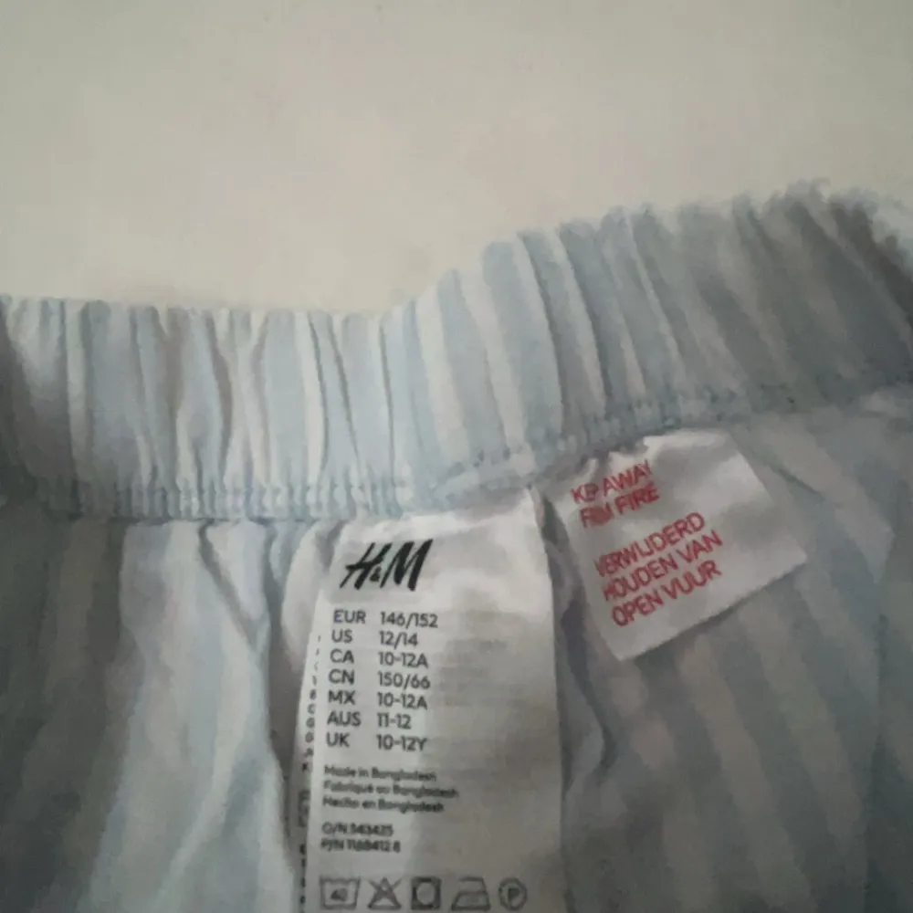 Säljer ett par ljusblå och vita randiga byxor från H&M. De har en bekväm elastisk midja med snörning för justerbar passform. Perfekta för en avslappnad stil! Inprincip oanvända.. Farkut & Housut.