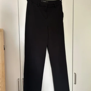 Svarta kostymbyxor - Säljer ett par stilrena svarta kostymbyxor. De är medelmidjade och har en klassisk straight passform. Perfekta för både kontoret och festligare tillfällen. Byxorna har hällor för bälte och en diskret dragkedja framtill.