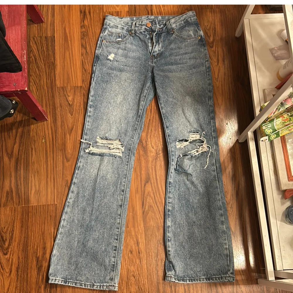 Säljer ett par blå jeans från Shein i storlek XS. De har en cool distressed look med slitningar på knäna och en bootcut-stil. Perfekta för en avslappnad vardagsstil. De är i bra skick och redo för en ny ägare!. Jeans & Byxor.