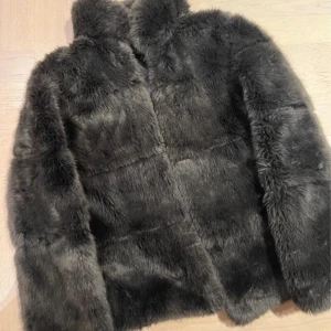 Mörkgrå pälsjacka från Zara Basic - Säljer en supermjuk och fluffig mörkgrön pälsjacka från Zara Basic. Perfekt för kalla dagar med sin mysiga känsla. Jackan har långa ärmar och en stilren design som passar både till vardags och fest. Ett måste för garderoben i vinter! 🖤
