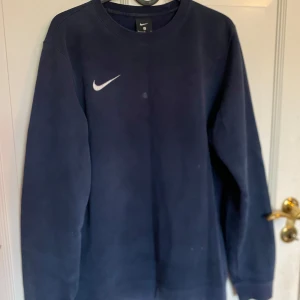 Mörkblå sweatshirt från Nike - Säljer en mörkblå sweatshirt från Nike i storlek S. Tröjan är i bra skick och har en klassisk Nike-logga på bröstet. Perfekt för både vardag och träning. Superbekväm och stilren design! (Har en liten fläk på bröstet, men går bort i tvätten. O tvättar såklart den vid köp.)