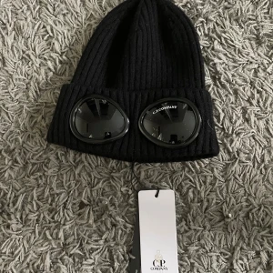 Oanvänd Cp Company Mössa - tjockt, tunnt, stretchigt material belt oanvänd med taggen och plast över linserna.