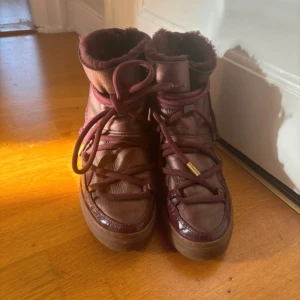 Inuikii skor  - Vinröda inuikii skor med kilklack. Storlek 38. I bra skick förutom lite slitage på sidorna (se bilder). Men inget som påverkar funktionen. 