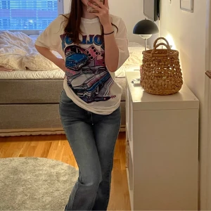 Vit t-shirt med retrotryck - Säljer en cool vit t-shirt med ett retrotryck på bilar och texten 'Roll On'. T-shirten har korta ärmar och en normal/oversized passform. Grym till exempelvis sommaren och att bara vara bekväm helt enkelt! 🚗✨Notera att tröjan är lite nopprig.