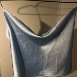 Ljusblå satin topp - Säljer en superfin ljusblå satin topp som är perfekt för sommaren. Toppen är kort och passar perfekt till både vardag och fest. Ett måste i garderoben för alla som älskar stil och komfort! 💙aldrig använt