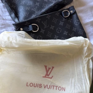 Svart axelväska L - Säljer en snygg svart axelväska L med det klassiska monogrammönstret. Väskan har en justerbar axelrem och en praktisk dragkedja. Perfekt för både vardag och fest! Kommer med originalpåse.