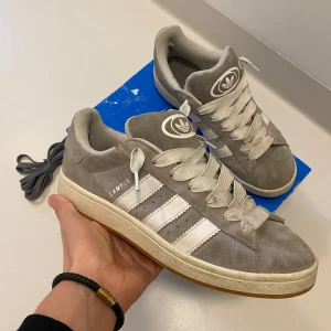 Adidas campus 00s - Riktigt feta gråa adidas campus som är i relativt bra skicka har små hål vid hälen på båda skorna men inget som syns när de är på annars är dom i bra skick, låda och extra snören ingår, skriv vid minsta fråga eller fundering🔥👍
