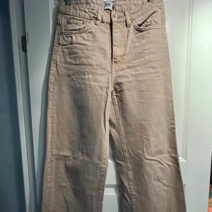 Beige byxor från lager 157 - Säljer ett par snygga beige byxor från Lager 157 i storlek S. Byxorna har en hög midja och en straight passform som ger en klassisk look. Perfekta för både vardag och fest! De är i bra skick och redo för en ny ägare. Passa på att fynda dessa stilr