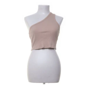 Beige oneshoulder ribbad topp - Säljer en beige oneshoulder topp som är ribbad och croppad. Perfekt för sommaren eller en festkväll. Toppen är tight och framhäver figuren på ett stilrent sätt. Materialet är mjukt och stretchigt, vilket gör den bekväm att bära.