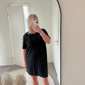 Svart t-shirtklänning med tryck - Säljer en svart t-shirtklänning med coolt tryck på baksidan. Klänningen är kortärmad och har en loose passform, perfekt för en avslappnad look. Materialet känns mjukt och bekvämt, troligen bomull eller en bomullsblandning. Perfekt för vardagsbruk eller en chill festkväll. 🖤