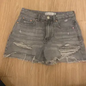 Säljer ett par grå jeansshorts från Stradivarius i storlek 36. De är i en vintage-stil med slitna detaljer och fransig kant. Perfekta för sommaren! 🩳