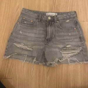 Grå jeansshorts från Stradivarius - Säljer ett par grå jeansshorts från Stradivarius i storlek 36. De är i en vintage-stil med slitna detaljer och fransig kant. Perfekta för sommaren! 🩳