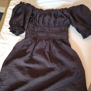Svart off-shoulder klänning i storlek XS - Säljer en superfin svart off-shoulder klänning i storlek XS. Klänningen har korta puffärmar och en tight passform i midjan som ger en snygg siluett. Perfekt för fest eller andra speciella tillfällen. Materialet känns lätt och bekvämt. Passa på att fynda denna stiliga klänning!