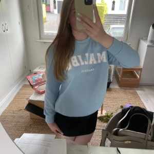 Blå hoodie - Denna vackra ljus blåa hoodie men tryck på som säger *Malibu California* är en perfekt hoodie nu till hösten/ vintern. Den är i jätte bra skick och använd ett fåtal gånger. Materialet är flisaktigt på insidan och silikonaktigt på utsidan. 