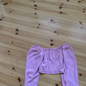 Rosa topp från Bik Bok - Säljer en söt rosa topp från Bik Bok i storlek XS. Toppen är gjord av ett mjukt och bekvämt material och har en fin struktur. Den har långa ärmar och en croppad passform, perfekt för både vardag och fest. Toppen är i nyskick och redo för en ny ägare!