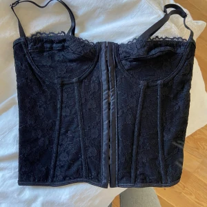 Svart korsett-topp - Säljer denna snygga korsett-topp i spets då den tyvärr inte kommer till användning. Den är helt ny, endast testad. Storlek XS men passar även en S. Ett + är att den har justerbara axelband! Säljer den för 99kr. Hör av dig för fler bilder/mer info!