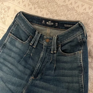 Straight jeans från Hollister  - Ett par mörkblåa högmidjade straighta jeans från Hollister med snygga insydda veck vid midjan både fram och bak, i storlek W24, L27