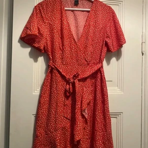 Klänning  - En röd klänning med vita prickar. Klänningen har en V-ringning och en skärp i midjan. Den har korta ärmar.  Märke: Shein  Storlek M och stretchiga, men skulle säga att den även funkar på en S.