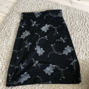 Svart blommig kjol från Hennes Collection - Säljer en svart kjol från Hennes Collection i storlek S. Kjolen har ett fint blommigt mönster i grått och är knälång. Perfekt för både vardag och fest! Den är i bra skick och väldigt bekväm att ha på sig. Passar bra till en enkel topp eller blus.