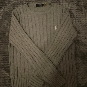 Grå kabel stickad tröja från Ralph Lauren - Säljer en fet kabel stickad Ralph lauren tröja. Säljer den pågrund av att den är för liten för mig använt sparmsat, inga defekter eller nått. Skriv vid frågor eller funderingar!