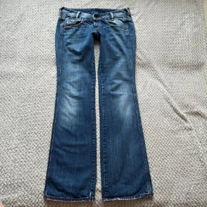 Blå bootcut jeans - Snygga blå bootcut jeans med låg midja och klassisk femficksdesign. Jeansen har en lätt slitning.