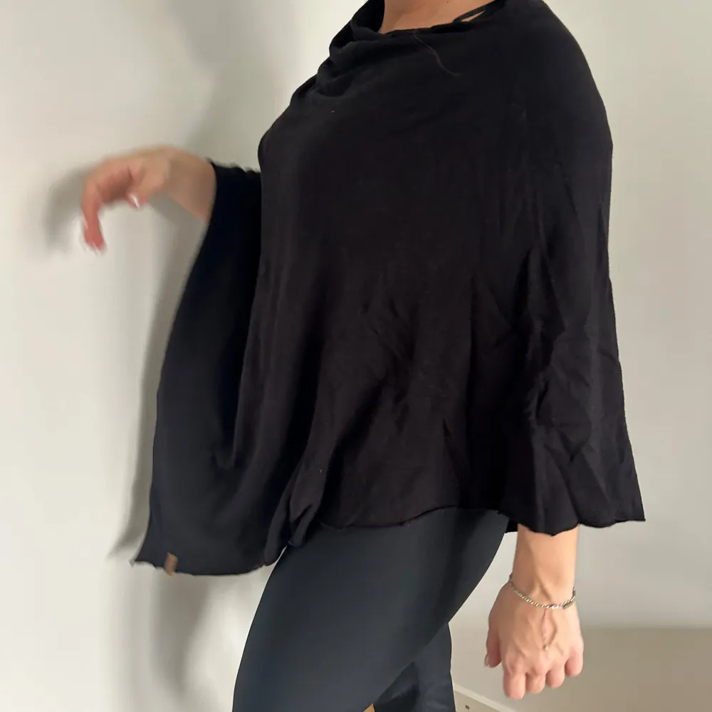 Snygg och stilren svart poncho perfekt för lager-på-lager-look. Den har en lös passform och är tillverkad i ett mjukt material som ger en skön känsla. Passar utmärkt för både höst och vår🖤. Neuletakit & Villapaidat.
