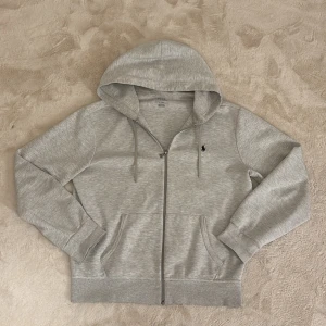  Ralph Lauren zip (grå) - Säljer en stilren grå huvtröja från Polo Ralph Lauren. Tröjan har en dragkedja framtill och en klassisk logga på bröstet. Den är tillverkad i mjukt material och har en justerbar huva med snören. Perfekt för en avslappnad look. Hör av dig vid funderingar och pris kan diskuteras mvh Malte