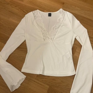 Vit långärmad topp med spetsdetaljer från Shein - Säljer en vit långärmad topp från Shein med v-ringning och spetsdetaljer. Grön tröja med knytning. Väldigt skönt material 