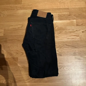 Svarta jeansbyxor från Levis - Snygga svarta jeansbyxor från Levis med klassisk femficksdesign och knappgylf. Perfekta för en stilren look. De har en rak passform och är tillverkade i slitstarkt denim. W28 L32