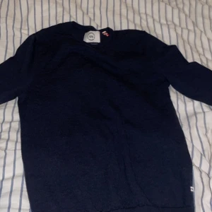 Mörkblå merinoulltröja från Kronstadt - Säljer en stilren mörkblå tröja från Kronstadt i extra fin merinoull. Tröjan har en klassisk design med rund hals och långa ärmar, perfekt för kyligare dagar. En tidlös favorit i garderoben!