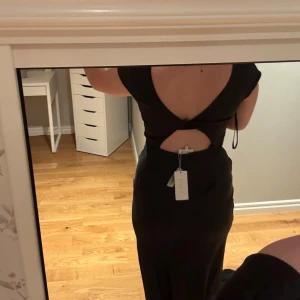 Svart långklänning med öppen rygg - Hej, säljer denna fina balklänning då jag har valt en annan. Helt oanvänd med prislapp kvar. Den är i storlek M och här är måtten för den.  Byst:90-92 cm, Midja: 73-75 cm, Höft: 98-100 cm. Hör gärna av dig om du har frågor eller vill ha mer bilder❣️