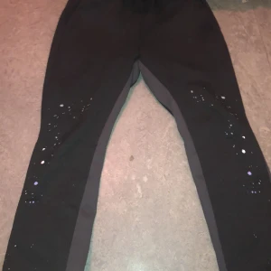 Svarta träningsbyxor med detaljer - Snygga svarta träningsbyxor med glittrande detaljer längs benen. Perfekta för att ge lite extra stil till din träningsgarderob. Byxorna har en bekväm passform och är gjorda i ett stretchigt material för optimal rörelsefrihet.