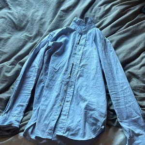 Blå skjorta från Ralph Lauren - Säljer en stilren blå skjorta från Ralph Lauren i slim fit. Skjortan har långa ärmar och knappar framtill. Perfekt för en snygg och avslappnad look.
