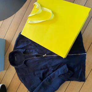 J.Lindeberg overshirt - Snygg mörkblå overshirt från J.Lindeberg med dragkedja framtill. Overshirten har en klassisk krage och långa ärmar med knappar vid ärmsluten. Perfekt för en stilren look. Nypris 2600kr😊hör av er vid minsta fundering!!