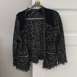 Svart och vit kofta från Gina Tricot - Snygg svart och vit kofta från Gina Tricot i storlek XS. Jackan har en fransig design med dragkedjor på fickorna och en öppen front. Perfekt för att ge din outfit en cool touch. 😎