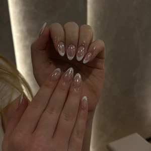 Franska naglar  - Bilden visar eleganta naglar med en fransk manikyrstil. Naglarna är mandelformade och har en glansig finish med vita toppar. Perfekt för en stilren och klassisk look.