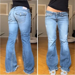 Blå bootcut jeans från True Religion - Säljer ett par blå bootcut jeans från True Religion. De har en låg midja och slitna detaljer för en cool look. Jeansen har knappar och dragkedja framtill💓