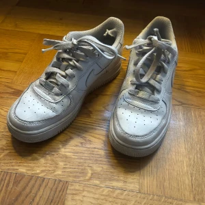 Vita Nike Air Force sneakers - Säljer ett par klassiska vita Nike Air Force sneakers. Skorna har en stilren design med snörning och den ikoniska Nike-loggan på sidan. Perfekta för en avslappnad stil. I storlek 38. pris kan diskuteras.