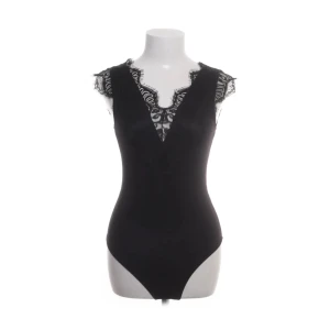 Svart spetsbody från Pieces - Svart body från Pieces med v-ringning och spetsdetaljer. Säljer då den inte kommit till användning.