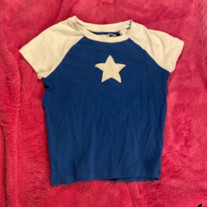 Blå och vit t-shirt med stjärna från Cropp - Snygg blå t-shirt från Cropp med vita ärmar och en stor vit stjärna på framsidan. 