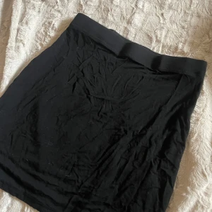 Svart minikjol - En enkel och stilren svart kjol med tight passform. Perfekt för en minimalistisk look. Kjolen är kort och har en elastisk midja för extra komfort.