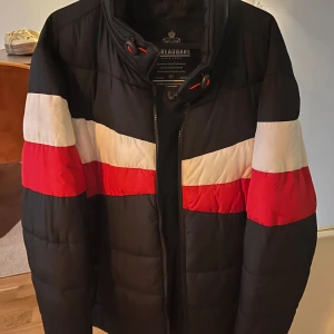 Svart pufferjacka från Threadbare - Säljer en svart pufferjacka från Threadbare med röda och vita sträck helt oanvänd jacka super bra skick 