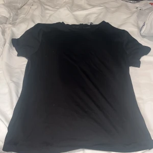 Svart t-shirt från H&M Divided - Säljer en klassisk svart t-shirt från H&M Divided. Perfekt basplagg med korta ärmar och rund hals. Enkel och stilren design som passar till det mesta. Perfekt för en avslappnad look. Väldigt genomskinlig 